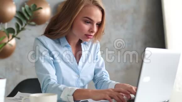 幸福的年轻成功女商人的肖像用双臂庆祝某件事快乐的女人坐在办公室看着视频的预览图