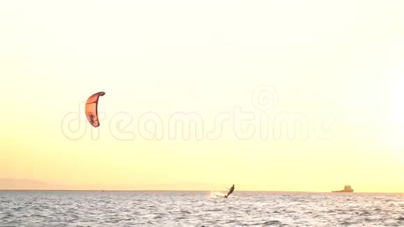 在五彩缤纷的灿烂日落中风筝在水面上滑行乘着风视频的预览图