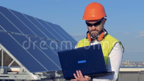 工人用他的笔记本电脑同时检查屋顶上的太阳能电池板4K视频的预览图