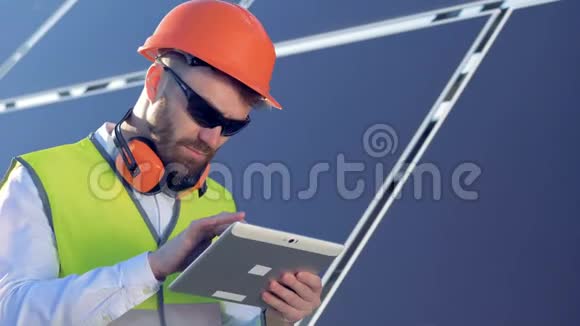 男性工人在他的平板电脑上打字而站在太阳能电池板附近的屋顶上4K视频的预览图
