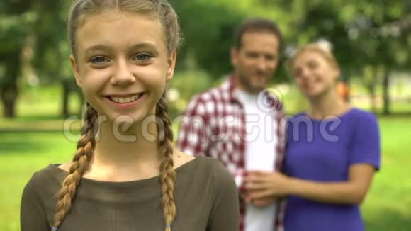 美丽的女孩在她幸福的父母爱和关心的家庭的背景下微笑视频的预览图