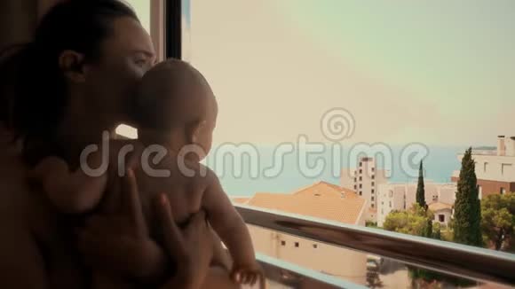 妈妈和她的小宝贝在度假时透过窗户望着大海视频的预览图