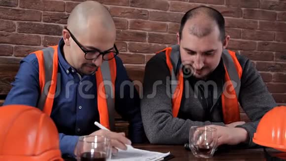 两个工程师坐在桌边喝咖啡聊天做笔记视频的预览图
