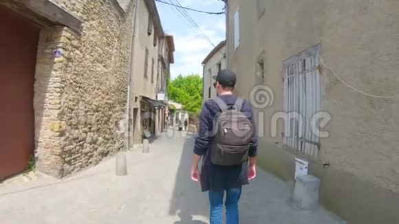 一个戴着帽子的年轻人走在法国卡卡松的古老街道上微笑着视频的预览图