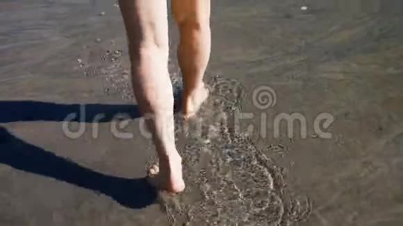 黄种人老人用黑沙在水中的岸边散步视频的预览图