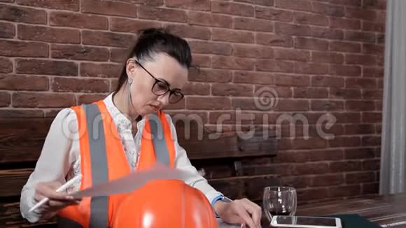 女工程师坐在桌子旁喝咖啡做笔记工作生产视频的预览图