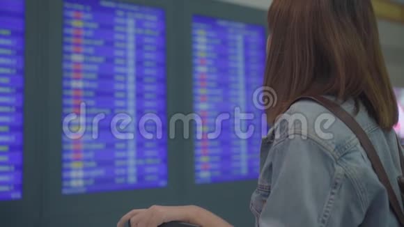 慢动作快乐的亚洲女人看着信息板检查她的航班与行李在候机大厅在出发视频的预览图