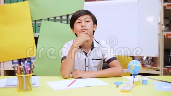 坐在书桌旁写笔记本的男孩视频的预览图
