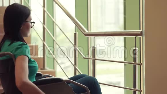 坐在轮椅上的孤独残疾女子望着窗外悲伤视频的预览图