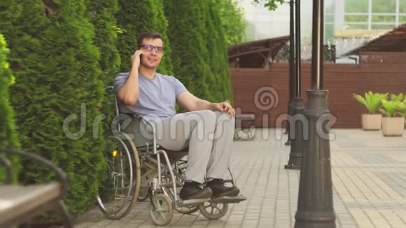 坐在轮椅上的有魅力的残疾人在电话里微笑着视频的预览图