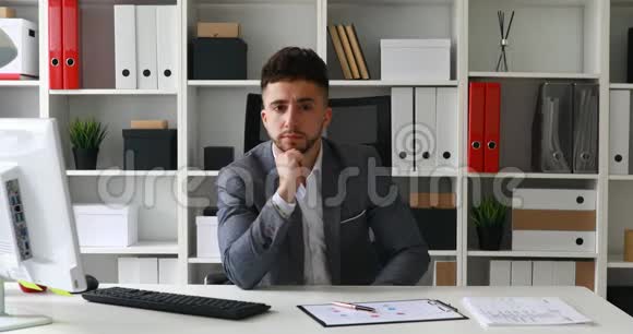 主任坐在白色办公室的桌子上把手放在额头上视频的预览图