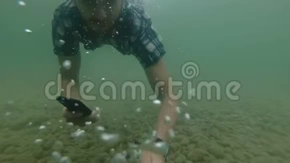 商人在水下慢动作使用智能手机天然湖泊视频的预览图