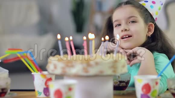 一个小女孩带着蜡烛微笑着看着蛋糕视频的预览图