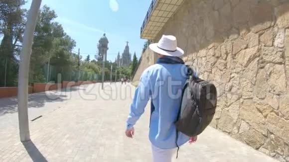 一个戴着背包帽子的年轻人去了西班牙巴塞罗那提比达博山上的圣心寺然后他转了一圈视频的预览图