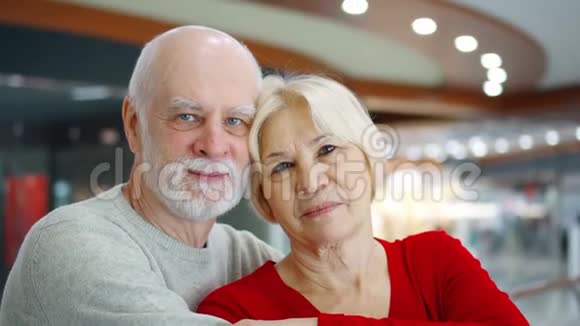 老两口站在商场看镜头在购物中心拥抱退休老人视频的预览图