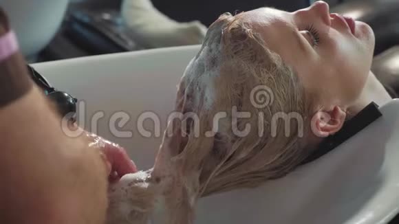 一位男造型师在一家现代美容店里给一个金发女人洗头视频的预览图