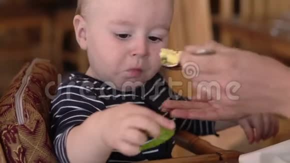 小宝宝坐在婴儿椅上吃食物视频的预览图