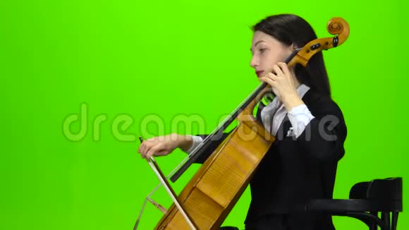 女孩坐着玩大提琴绿色屏幕侧视图视频的预览图