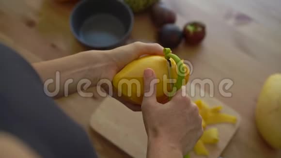 慢镜头拍摄一位年轻女子剥芒果和许多热带水果放在桌子上视频的预览图