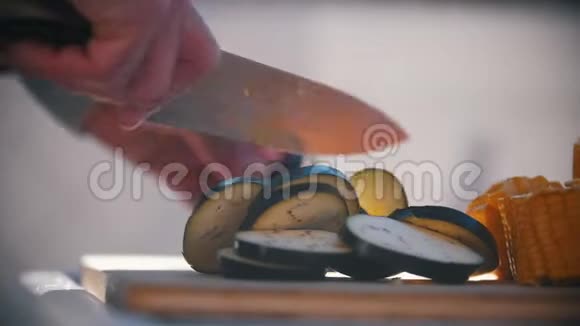 手男子切割茄子与刀特写背景上美味可口的新鲜蔬菜番茄视频的预览图