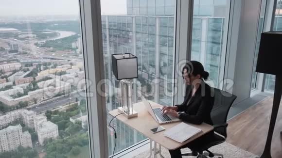 年轻女子在一个位于摩天大楼高层的现代化办公室工作商业女性在笔记本电脑上工作视频的预览图