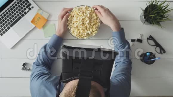 男人用VR耳机看电影吃爆米花视频的预览图