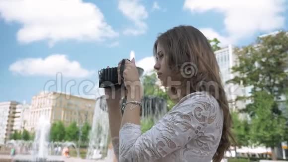 美丽的女孩用老式相机拍摄城市景点的照片视频的预览图