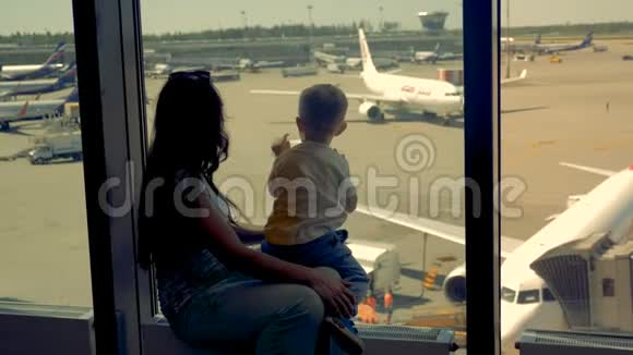 女人和男孩一起看机场的跑道关门一家人在看飞机的时候等待航班视频的预览图