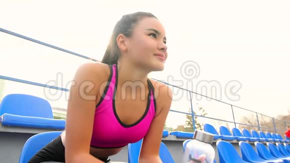 一个阳光明媚的日子年轻的亚洲运动员女孩正坐在体育场休息视频的预览图
