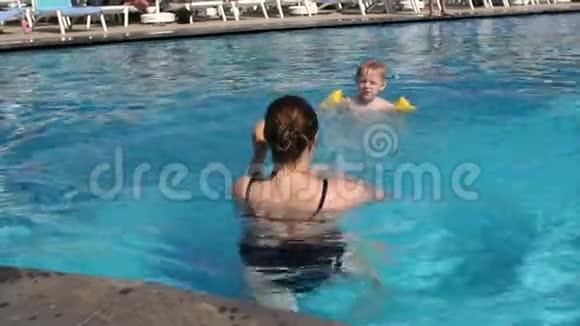 特写快乐妈妈教儿子在游泳池里游泳视频的预览图