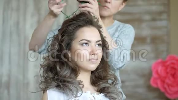 化妆师和模特一起工作一位造型师在女孩的模特头上戴一个红色狮子圈视频的预览图