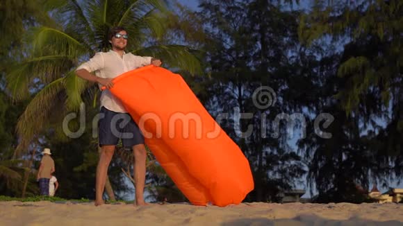 一个年轻人慢镜头在美丽的海滩上充气沙发视频的预览图