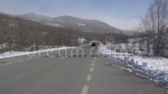一辆黑色汽车在冬天的路上行驶视频的预览图