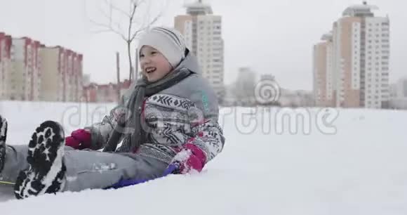 在寒冷的冬天一个快乐的女孩在白雪上骑雪橇视频的预览图