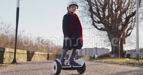 幸福微笑的女儿戴着安全帽的女孩在城市公园骑着Segway童年活跃安全视频的预览图