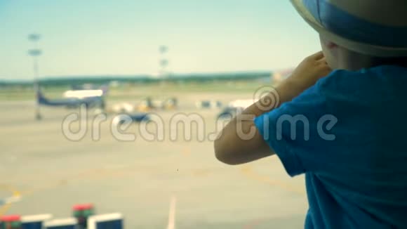 一个看飞机的孩子关门一个男孩坐着看机场跑道视频的预览图