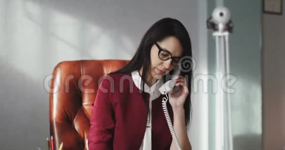 时尚的商务女性坐在皮椅上在电话里交谈视频的预览图