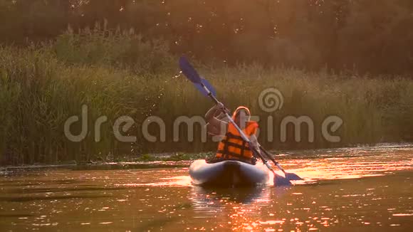 在夕阳下皮划艇上的一对人漂浮在河上慢动作视频的预览图