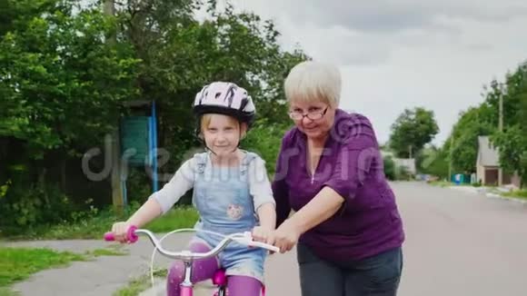 祖母教她孙女如何骑自行车儿童的第一次成功老年活动视频的预览图