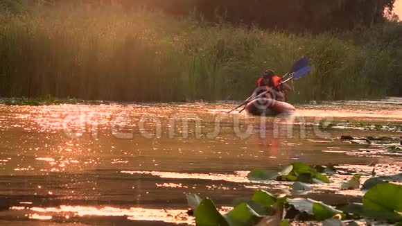 在夕阳下皮划艇上的一对人漂浮在河上慢动作视频的预览图