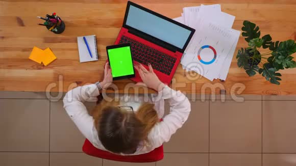 年轻的高加索员工使用平板电脑的特写镜头平板电脑前放着绿色的彩色屏幕视频的预览图