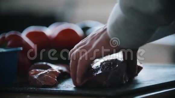 手男子切肉牛排用刀特写背景上美味可口的新鲜蔬菜番茄视频的预览图