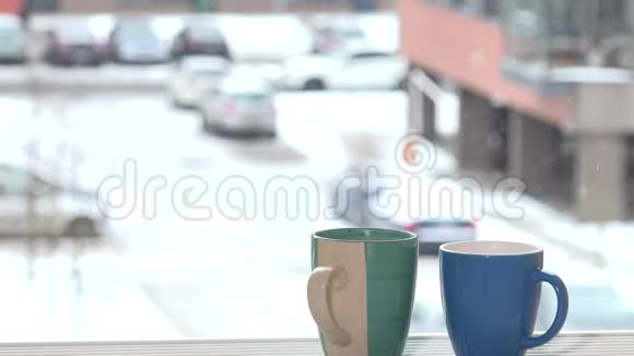 两杯咖啡茶热饮立在窗台上雪花飘落视频的预览图