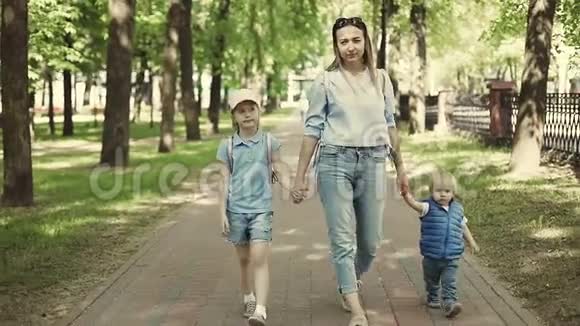 一位年轻的母亲正和孩子们在公园里散步慢动作视频的预览图