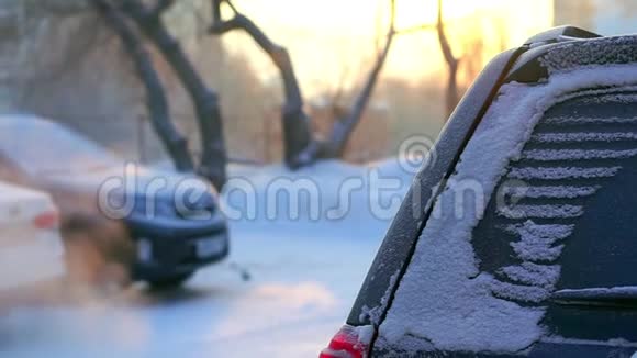 早上在房子的院子里冬天汽车抽烟在雪的周围阳光透过烟雾视频的预览图