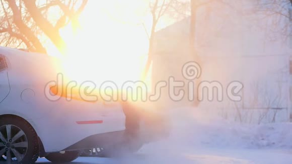 早上在房子的院子里冬天汽车抽烟在雪的周围阳光透过烟雾视频的预览图