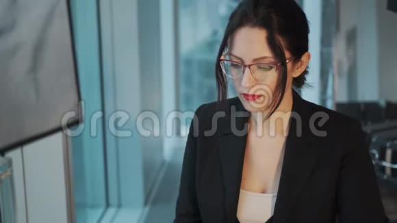一位穿着商务西装的年轻女性在工作场所的特写肖像商务女性坐在电脑旁视频的预览图