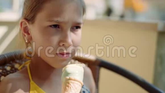 穿着黄色泳衣的快乐小女孩坐在阳台上吃冰淇淋4k视频的预览图