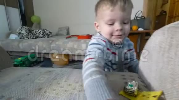 一个小男孩在扶手椅上玩他的玩具幼儿男孩在玩玩具汽车视频的预览图