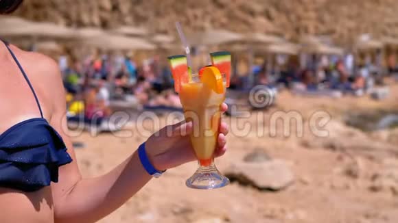 埃及海滩上手持异国情调果汁浴衣的少女视频的预览图